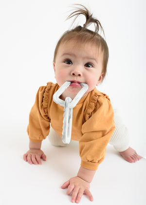 Baby girl crawls and uses BooginHead silicone chain link teether