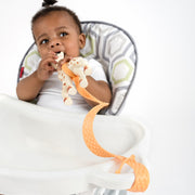 Baby product BooginHead SippiGrip Silicone in orange. Silicone strap holing toy to highchair. Easy to clean, bumps for soothing teething gums